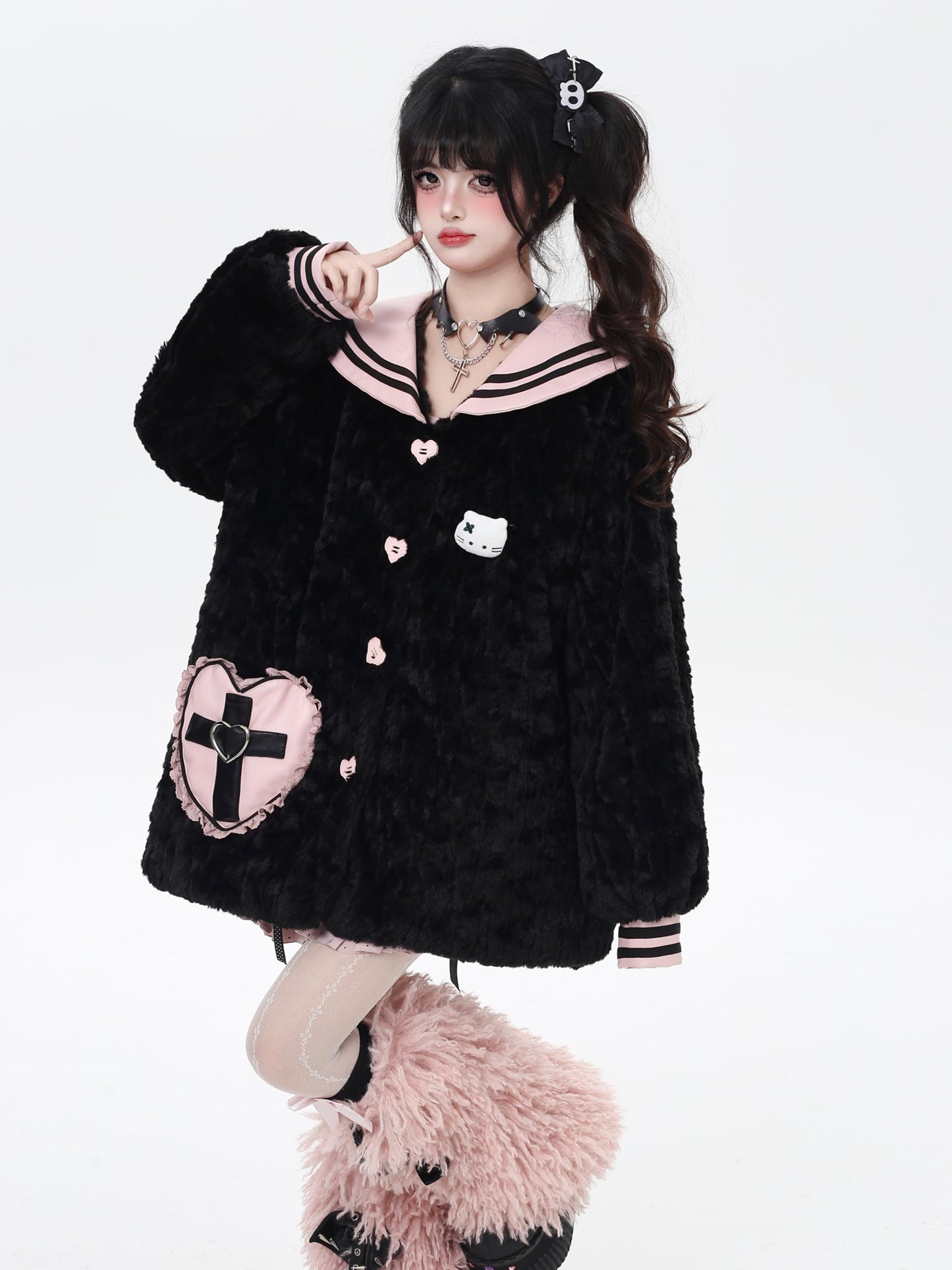 Person wearing a black plush jacket with heart and cross designs on a white background
