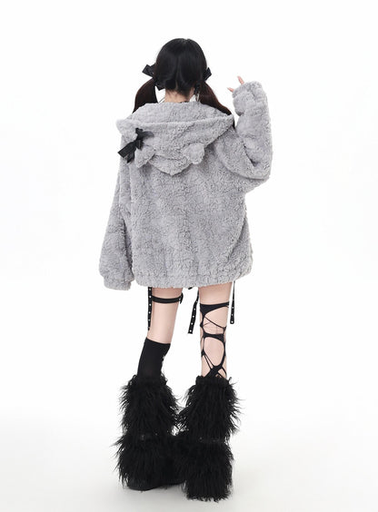 Person wearing a gray fluffy coat with a hood and black feathered boots on a white background