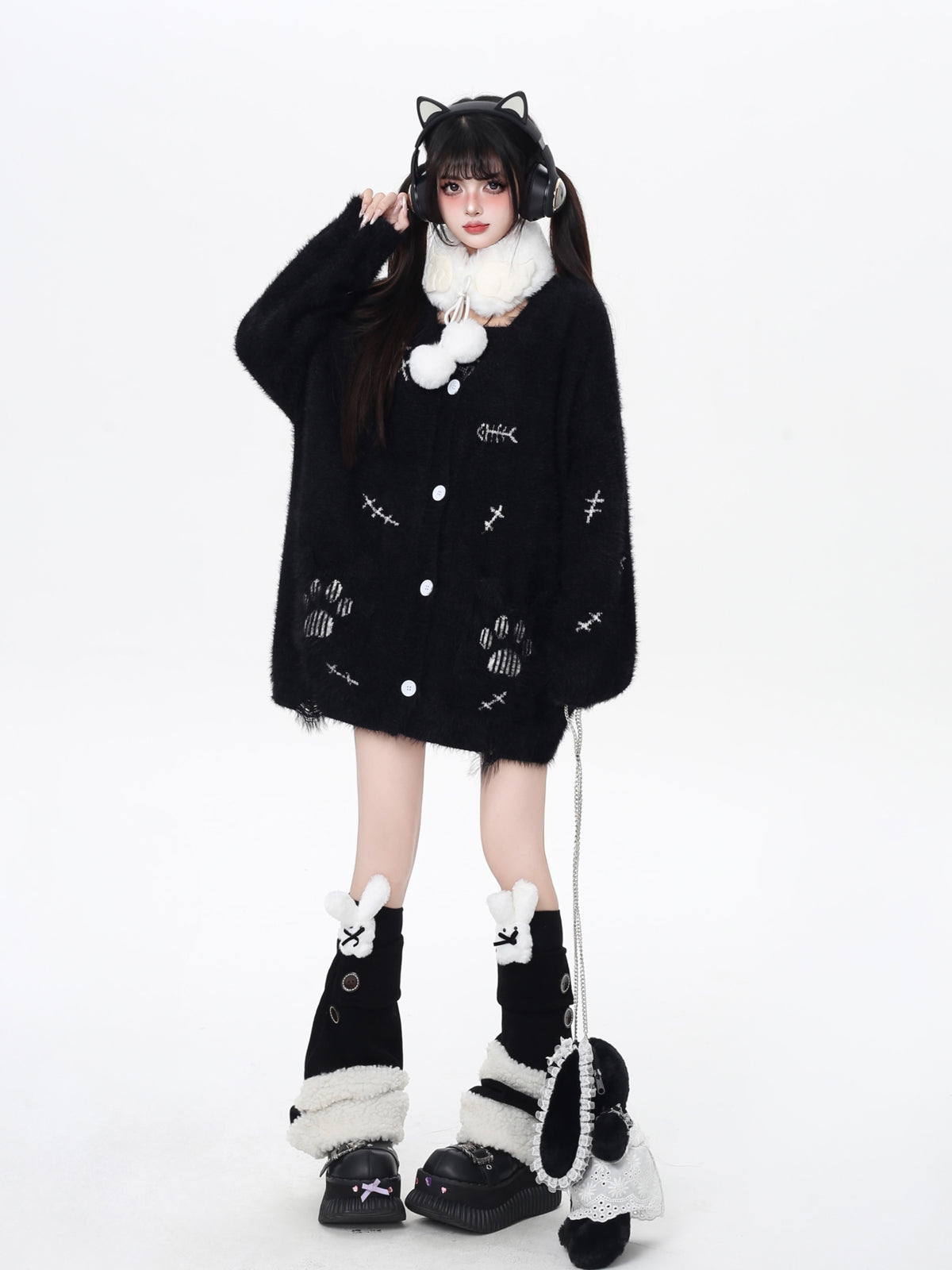 Person wearing a black outfit with white accents, including a coat, hat, and boots, on a white background.