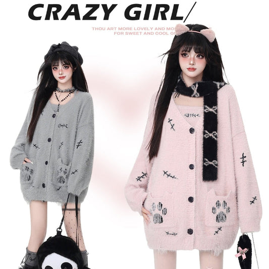 Two people wearing cardigans with cat-themed designs, one gray and one pink, on a white background.