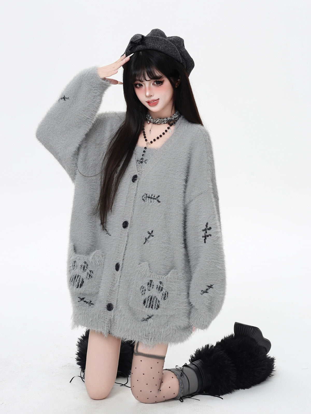 Person wearing a gray cardigan with cat paw designs on a white background