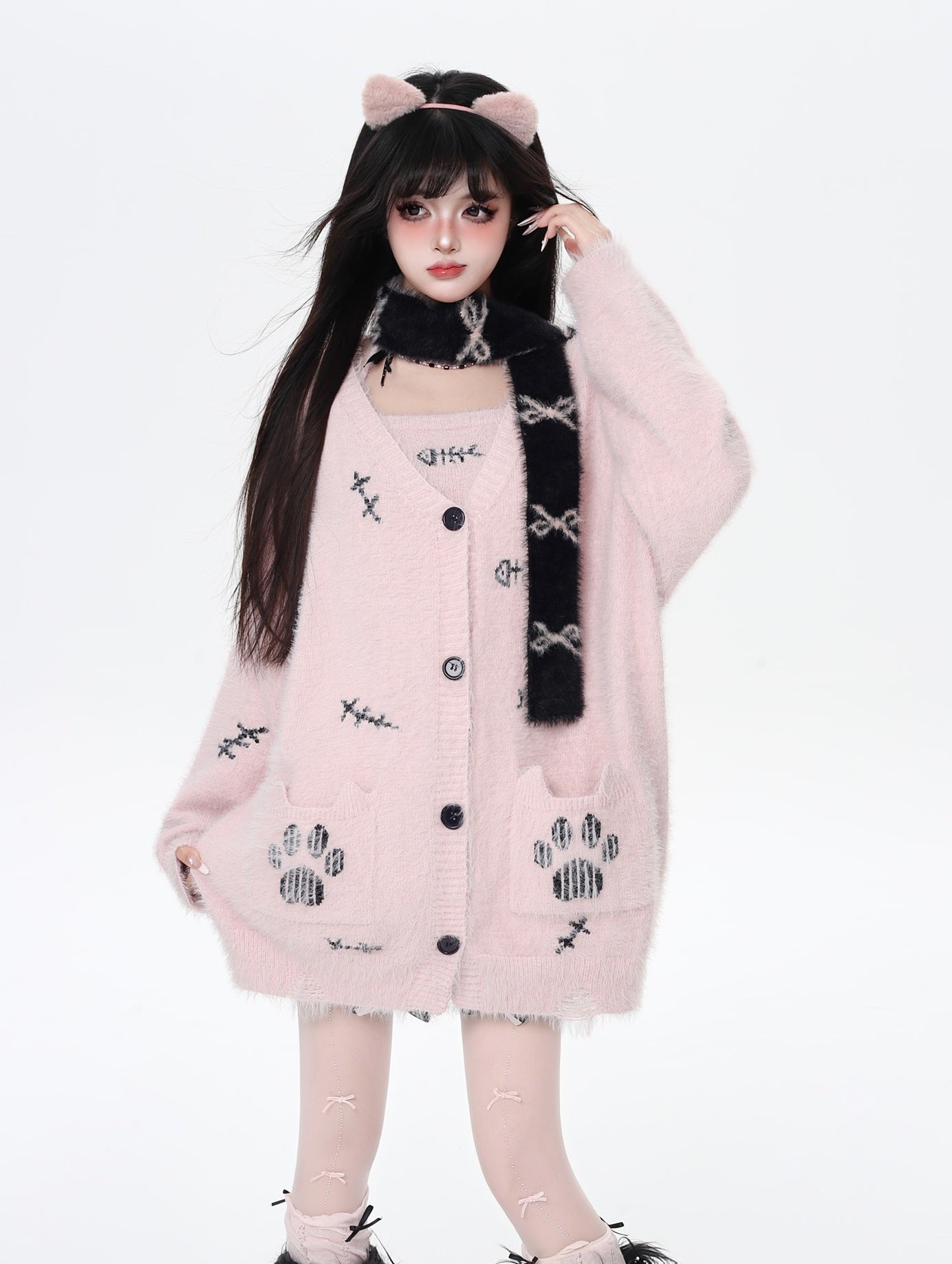 Person wearing a pink cardigan with paw print patterns on a white background
