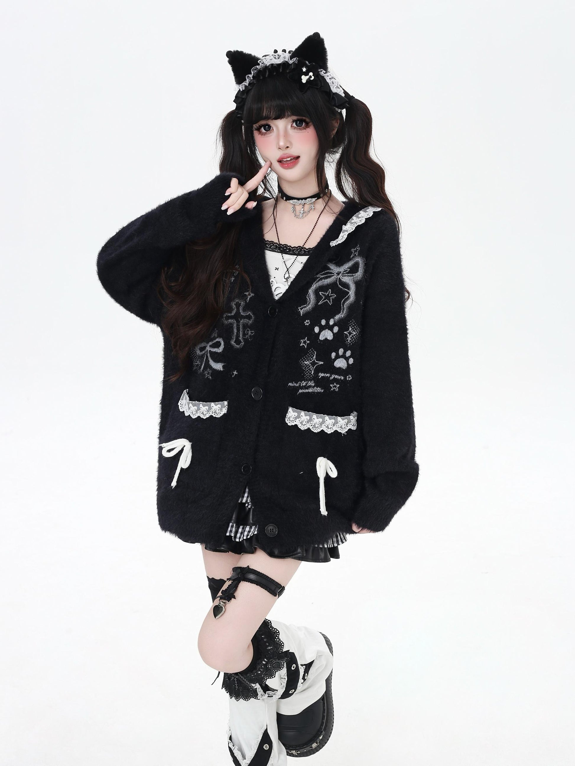 Person wearing a black cardigan with cat ears and paws on a white background