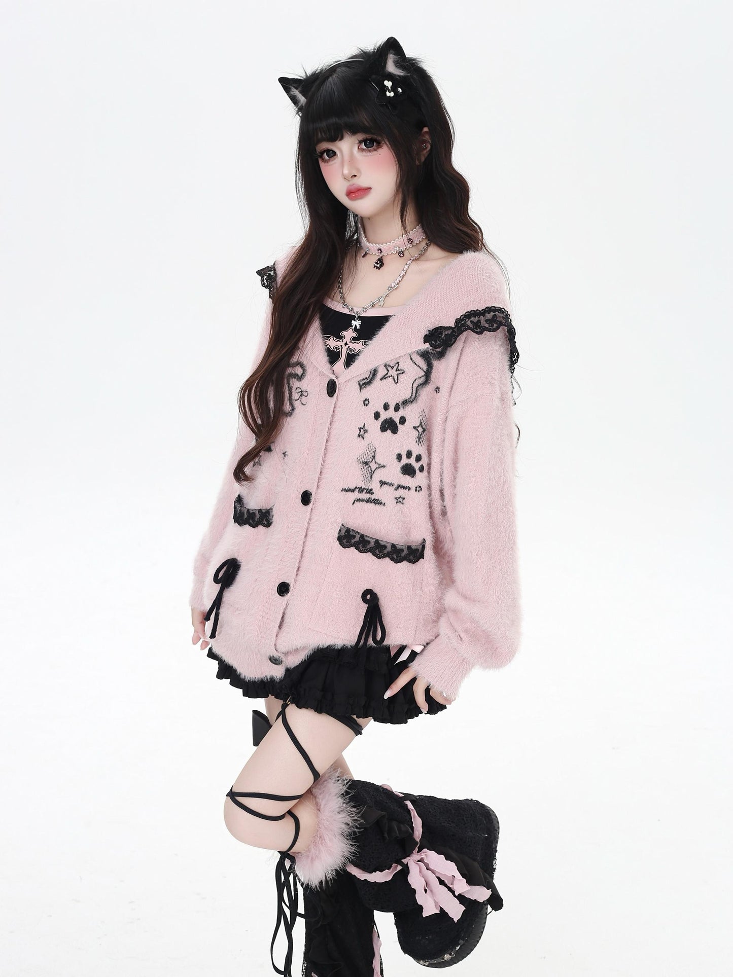 Person wearing a pink cardigan with black accents and cat ears on a white background
