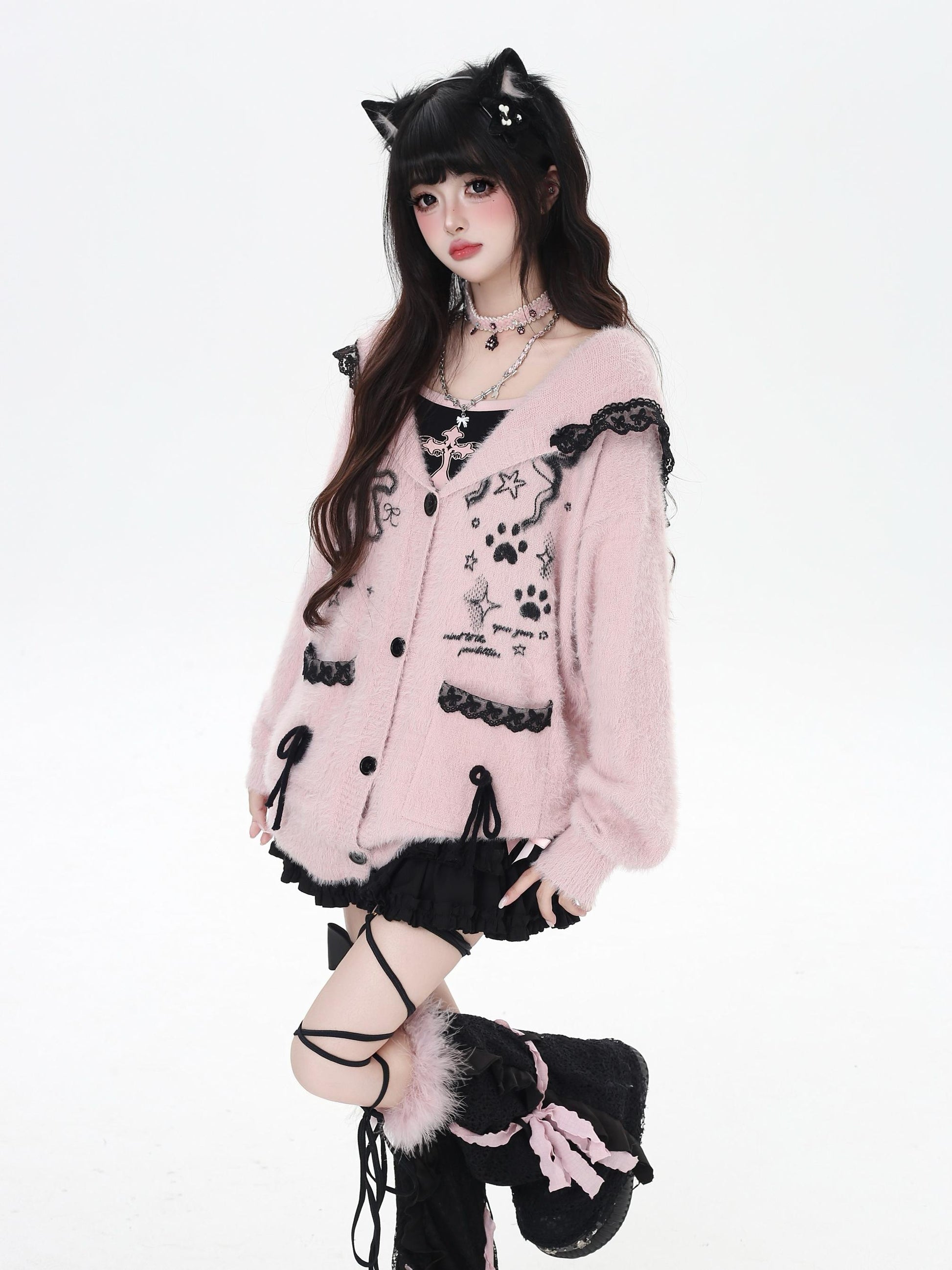 Person wearing a pink cardigan with black accents and cat ears on a white background