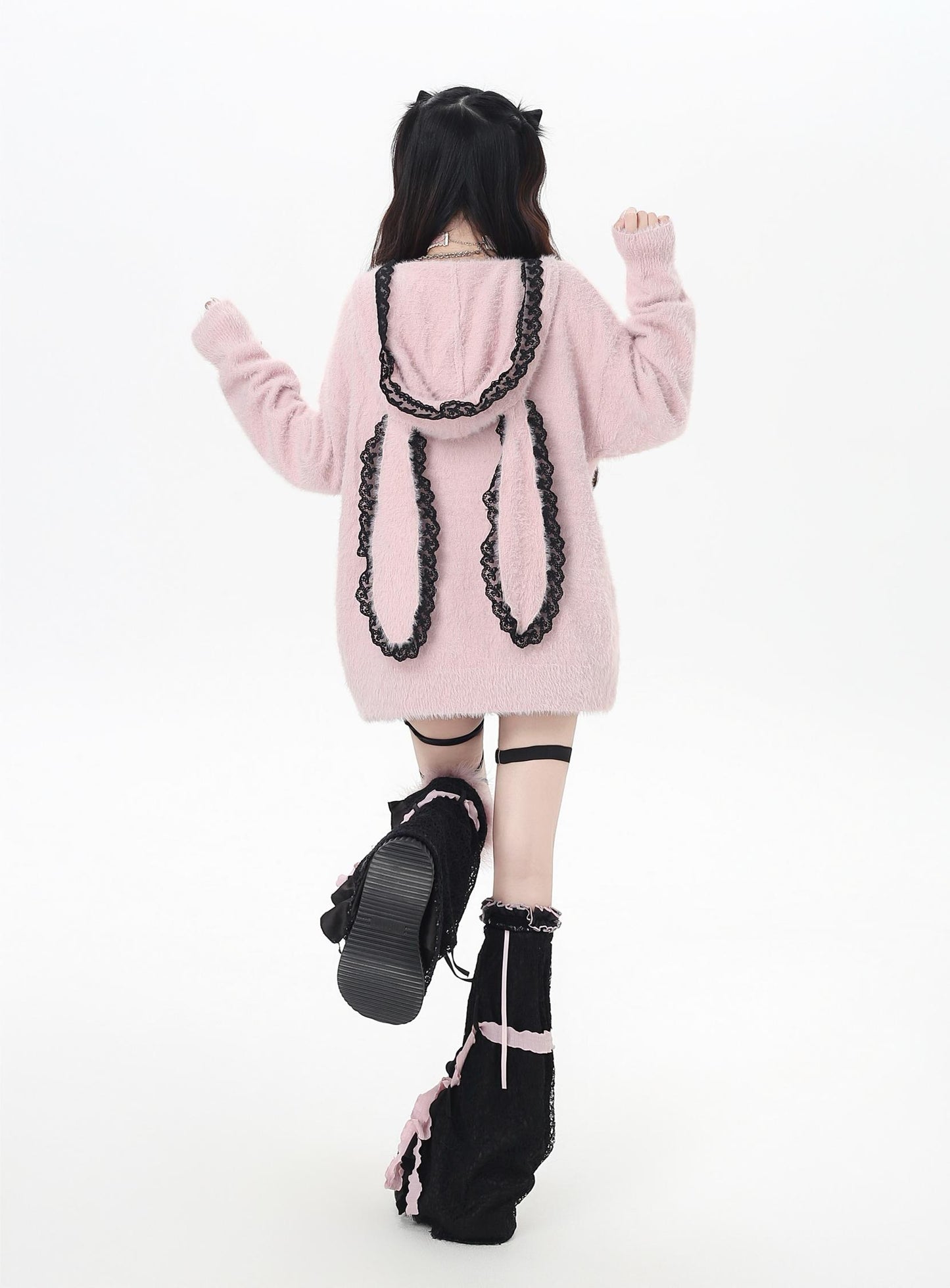 Person wearing a pink hoodie with black cat ears and tail on a white background