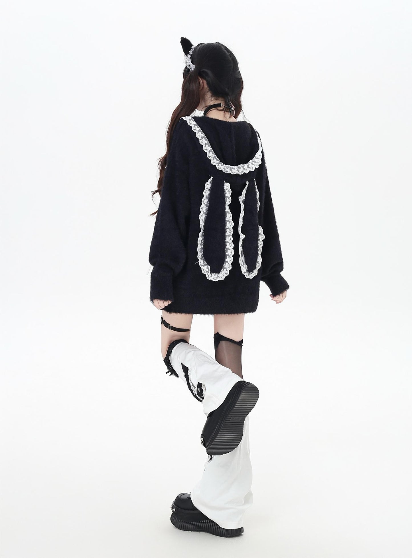 Person wearing a black sweater with white lace details on a white background