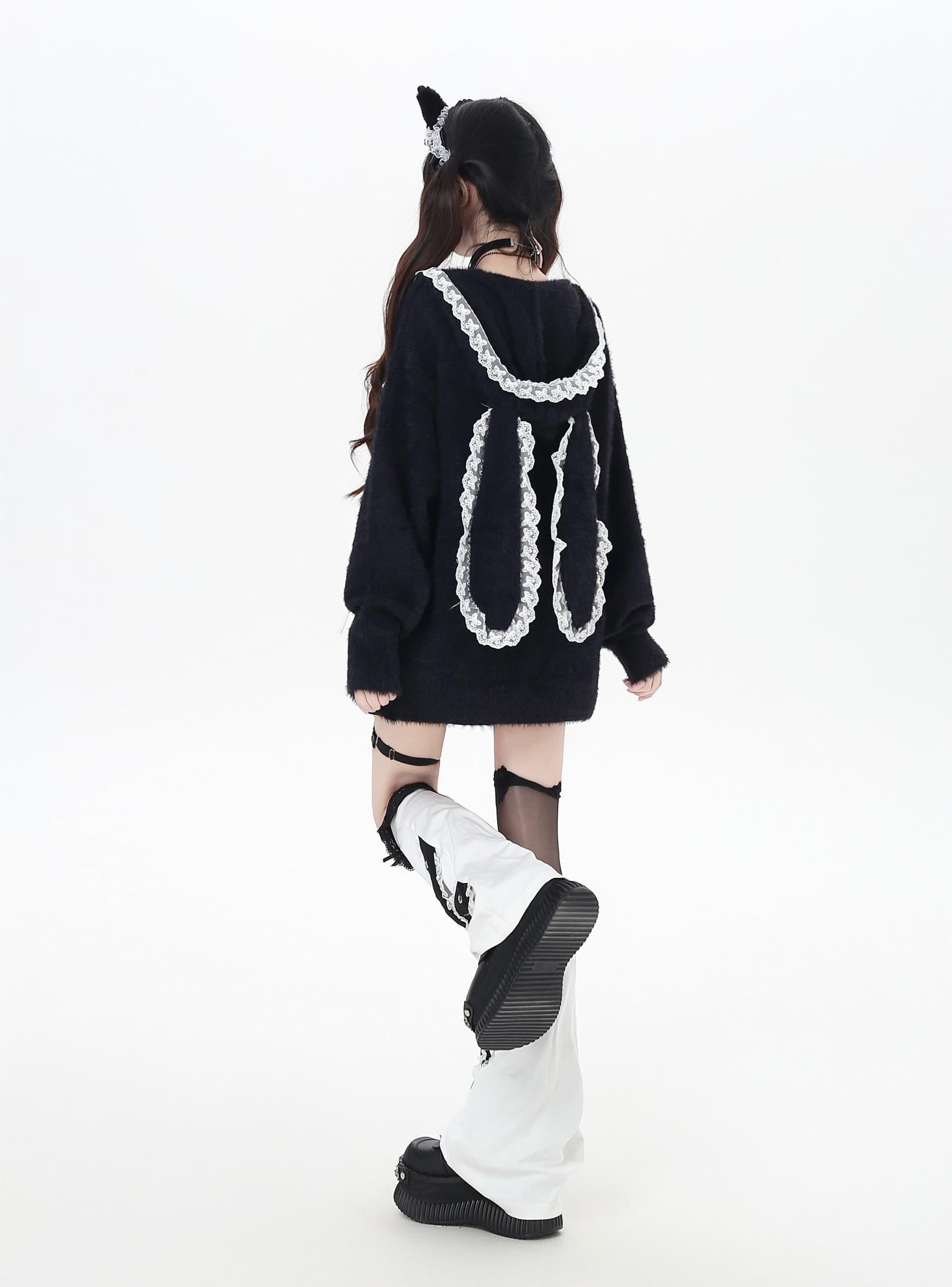 Person wearing a black sweater with white lace details on a white background