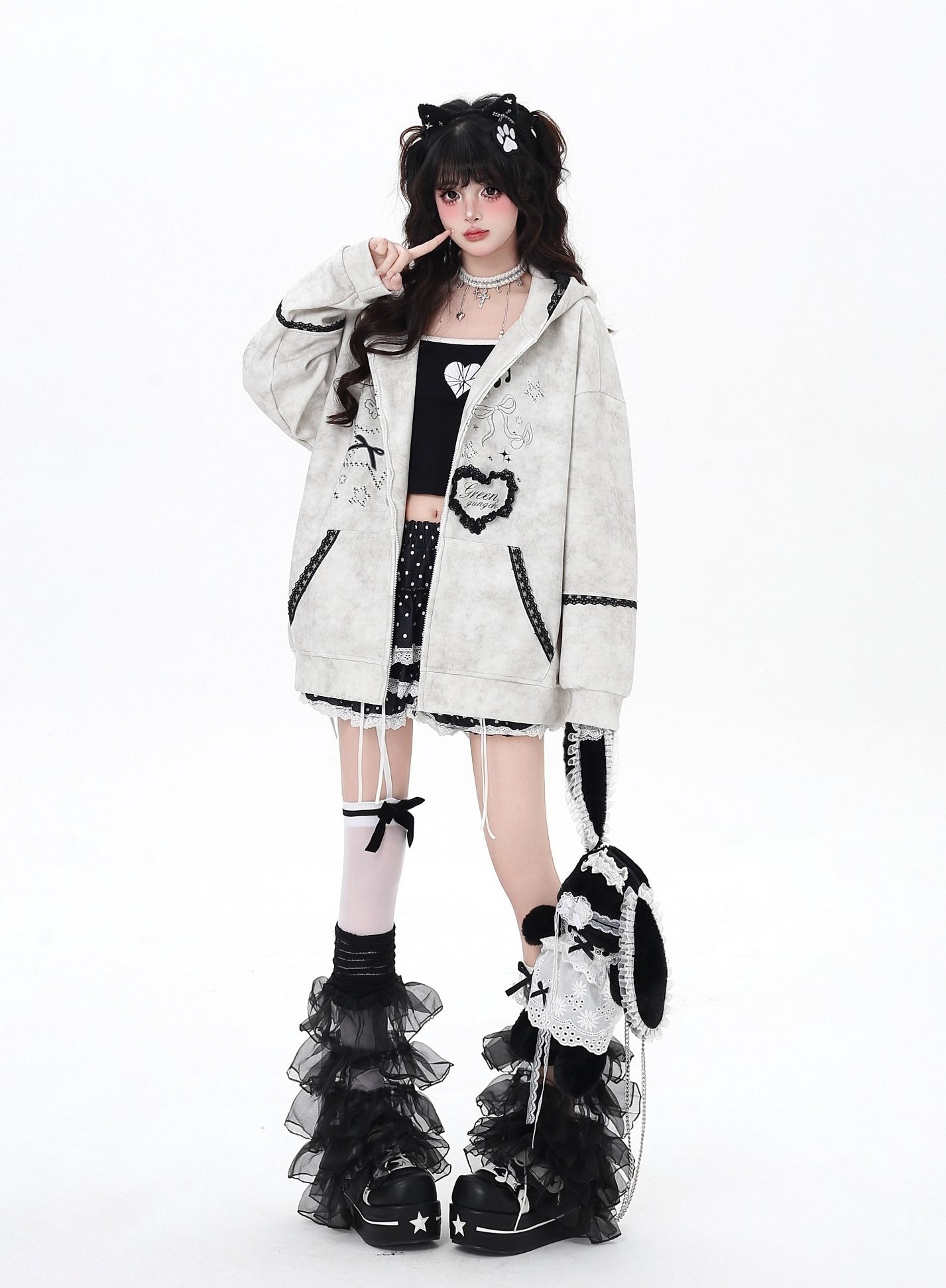 Person wearing a stylish outfit with a white coat, black and white shoes, and decorative accessories on a white background.