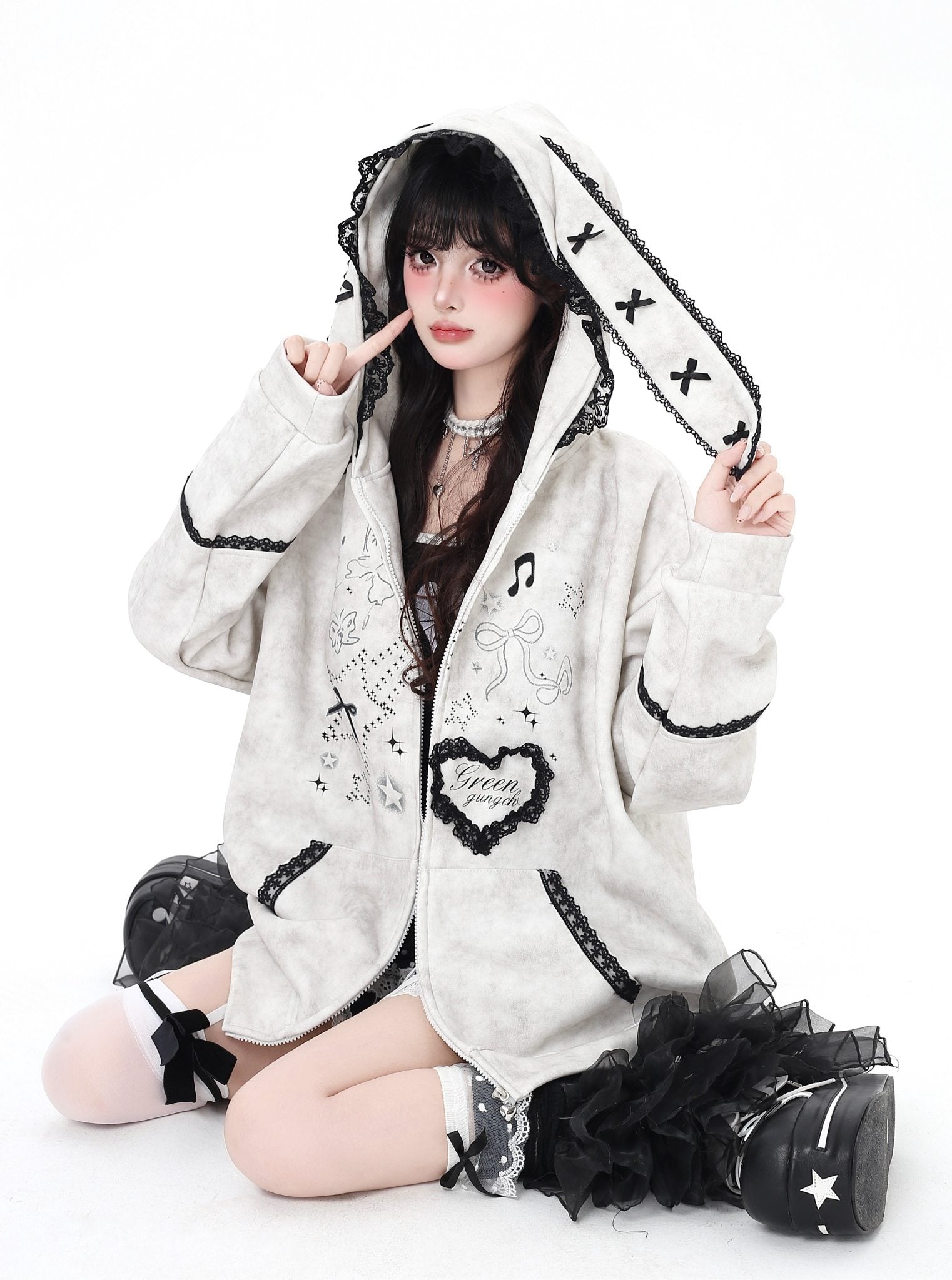 Person wearing a white hoodie with black accents and decorative elements on a white background