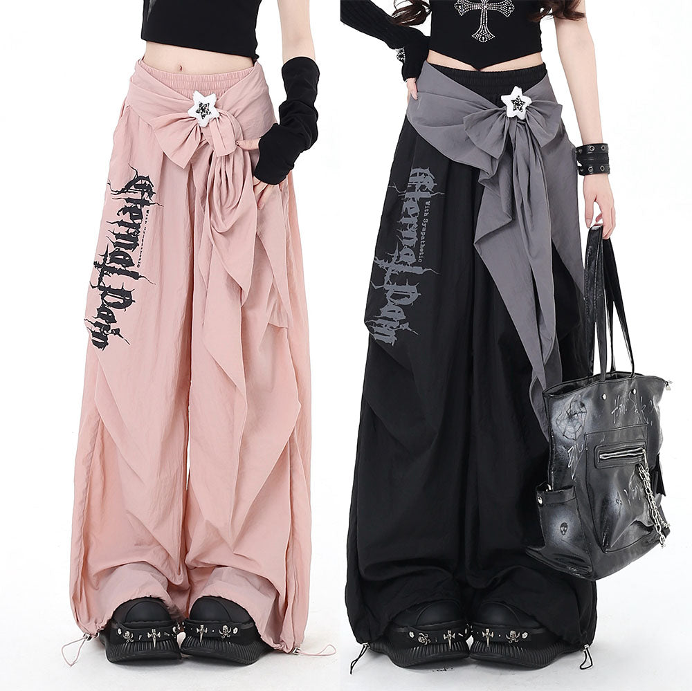 Two models wearing long, flowing pants with decorative elements on a white background.