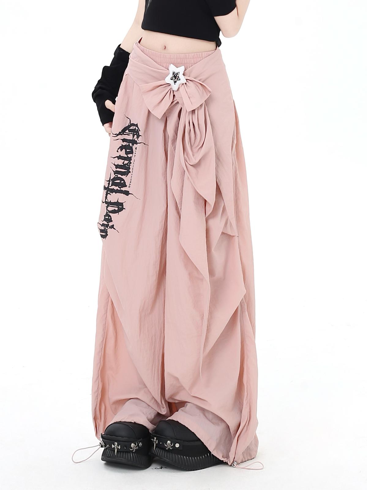 Long pink pants with a bow and text, worn by a person on a white background