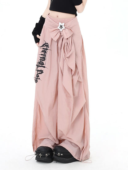 Long pink pants with a bow and text, worn by a person on a white background