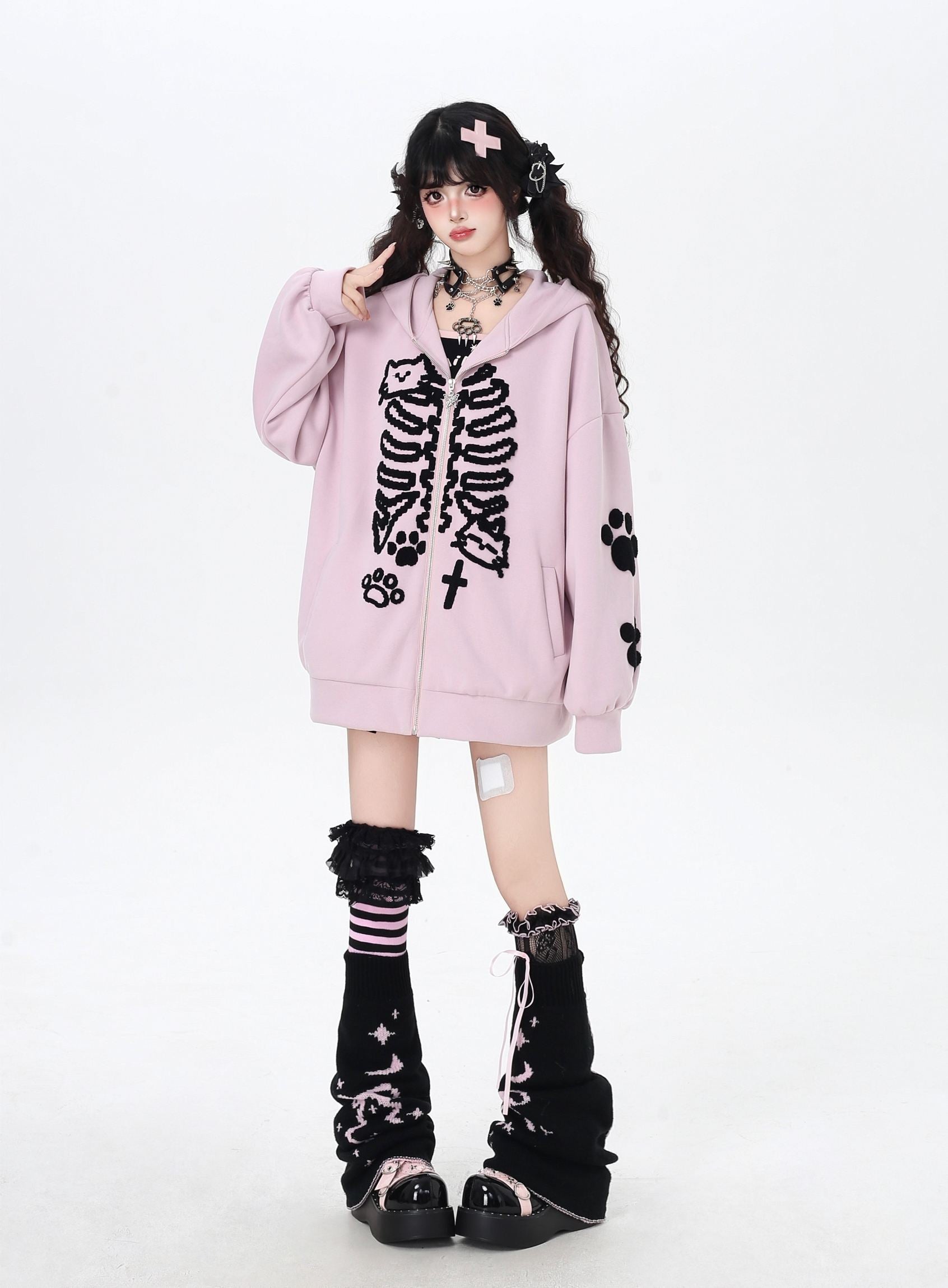 Person wearing a pink hoodie with black skeleton design on a white background