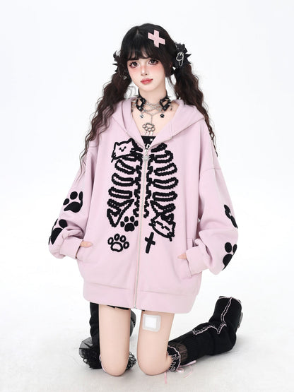Person wearing a pink hoodie with black skeleton and paw print designs on a white background