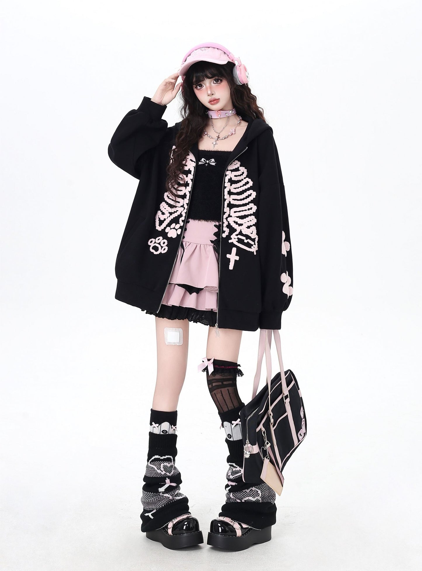 Person wearing a black skeleton cardigan with pink accents on a white background