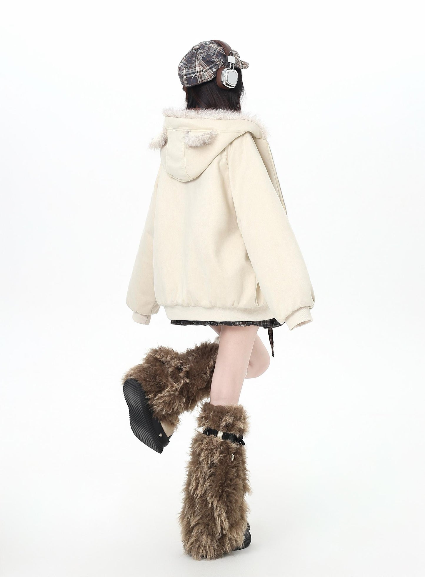 Person wearing a cream-colored hoodie and brown fur boots on a white background
