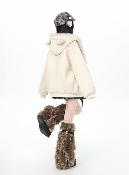 Person wearing a cream-colored hoodie and brown fur boots on a white background
