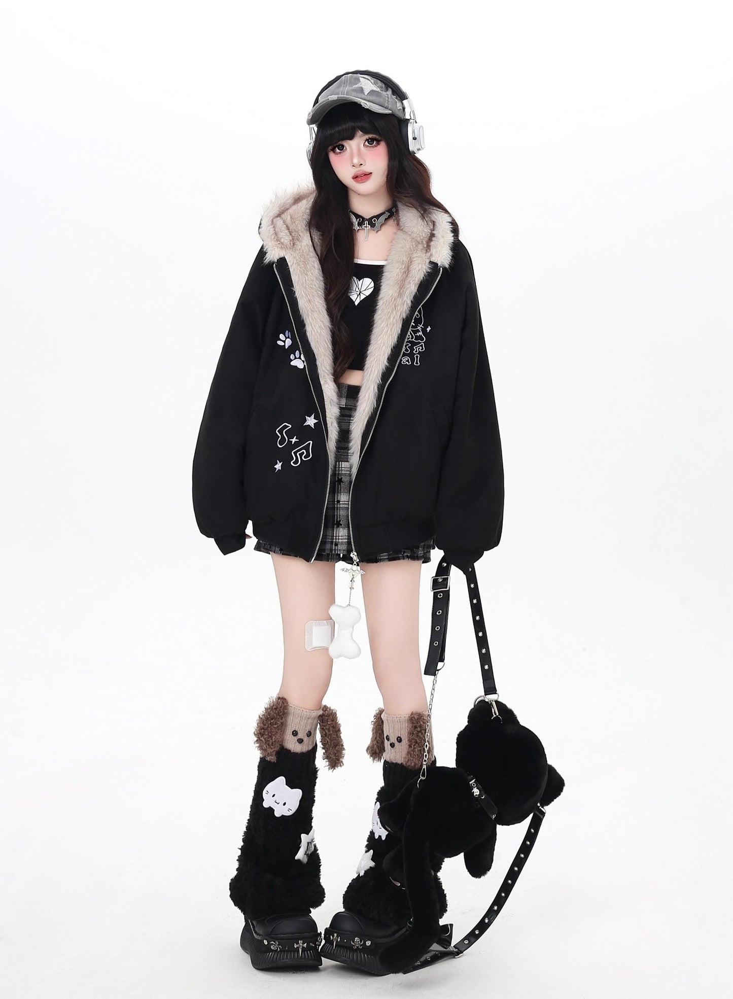Person wearing a black coat with fur trim, plaid skirt, and black boots on a white background