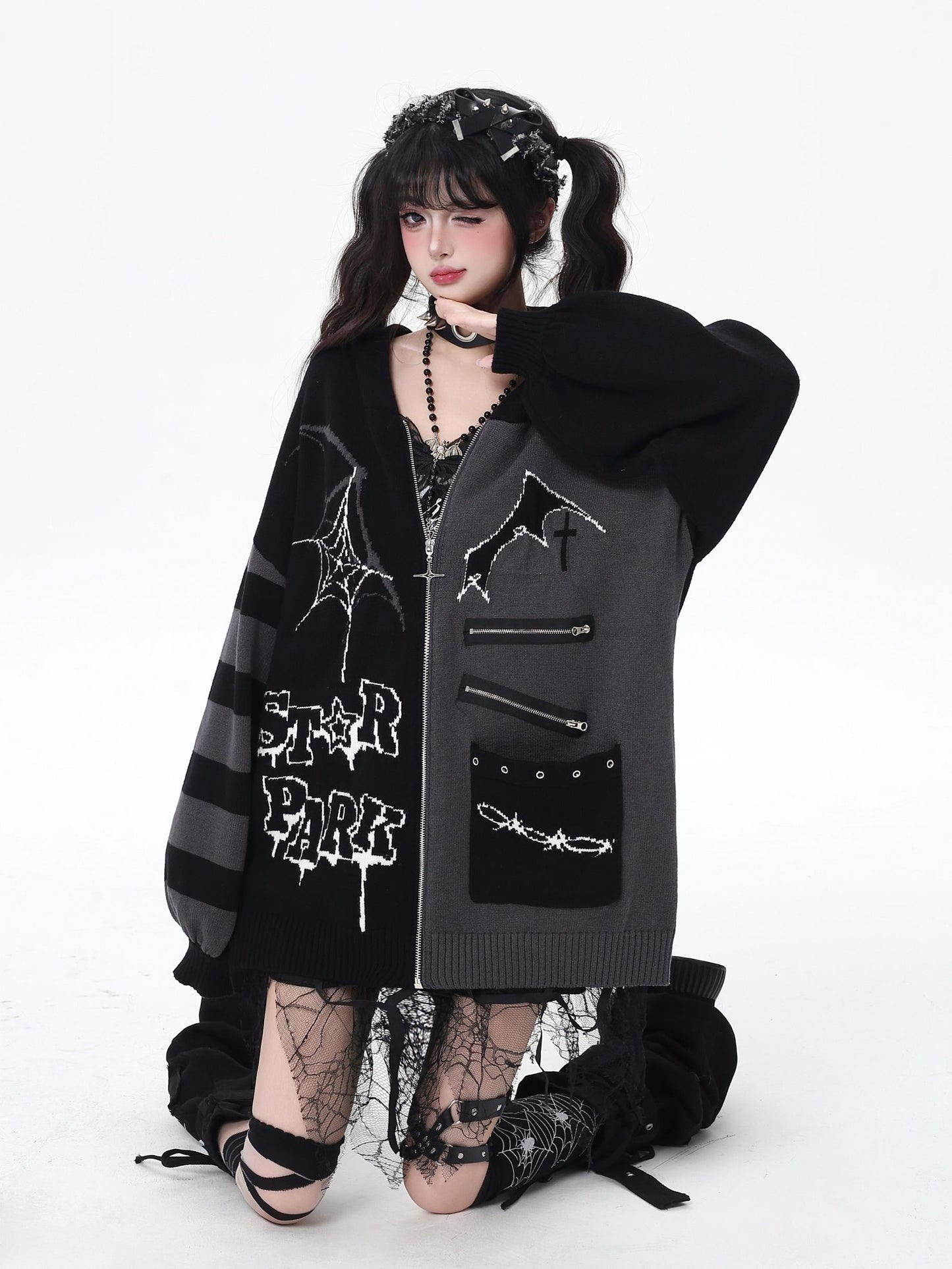 Person wearing a dark, stylish coat with spider web designs on a white background