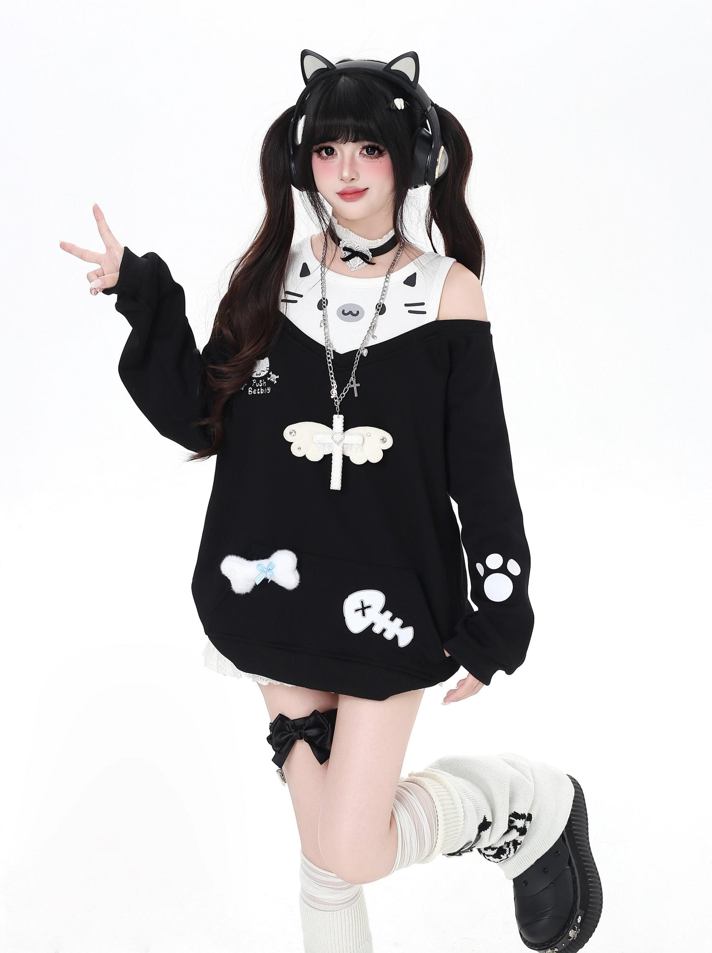 Person wearing a black and white cat-themed outfit with cat ears on a white background