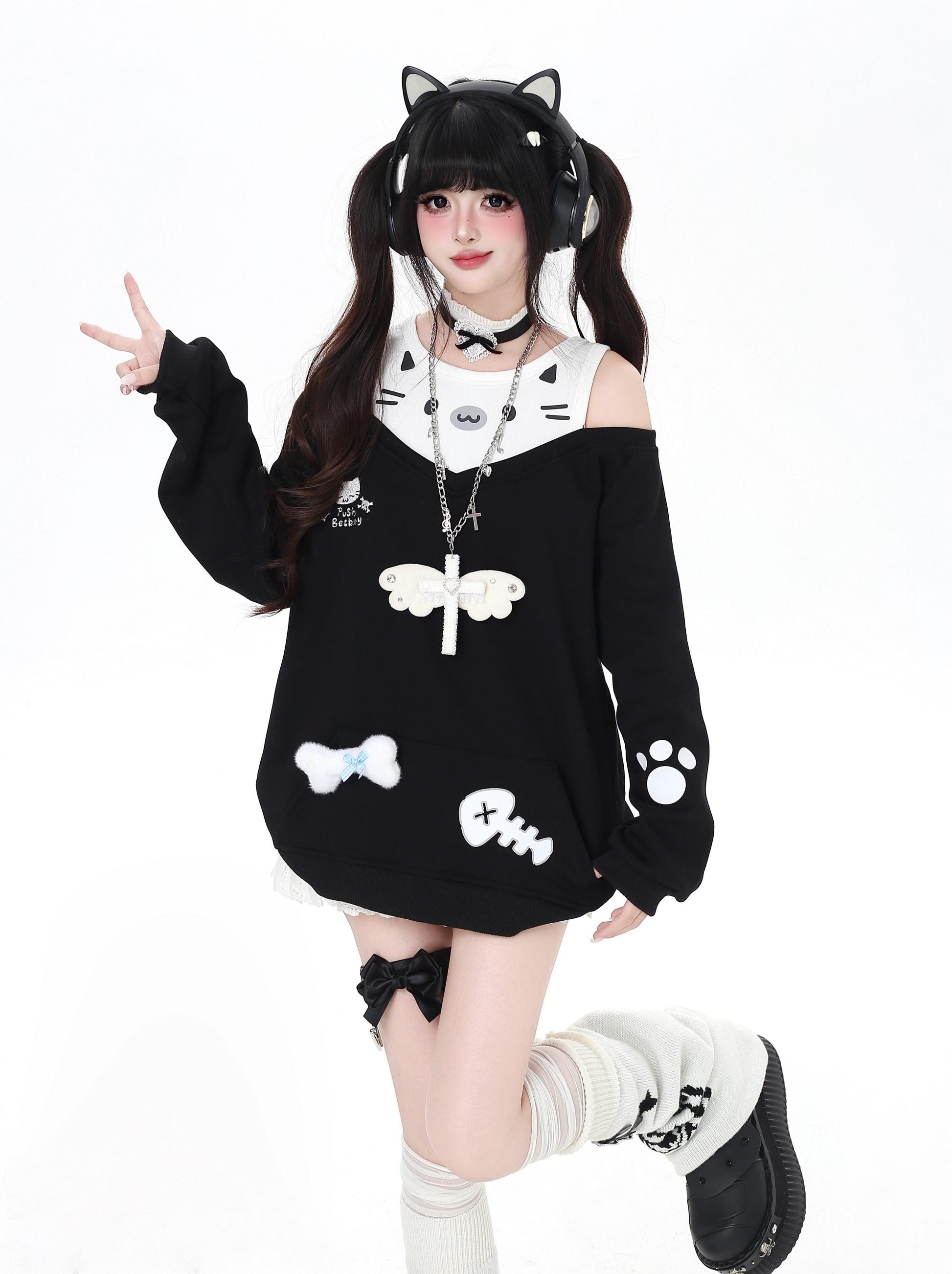 Person wearing a black and white cat-themed outfit with cat ears on a white background