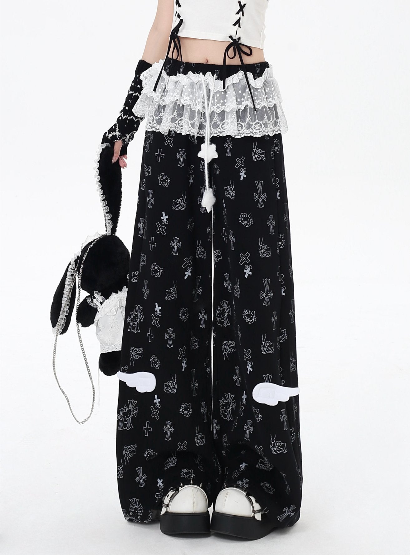 Person wearing black pants with white patterns and a white top, holding a plush toy.