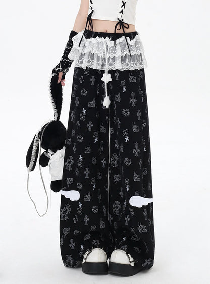 Person wearing black pants with white patterns and a white top, holding a plush toy.