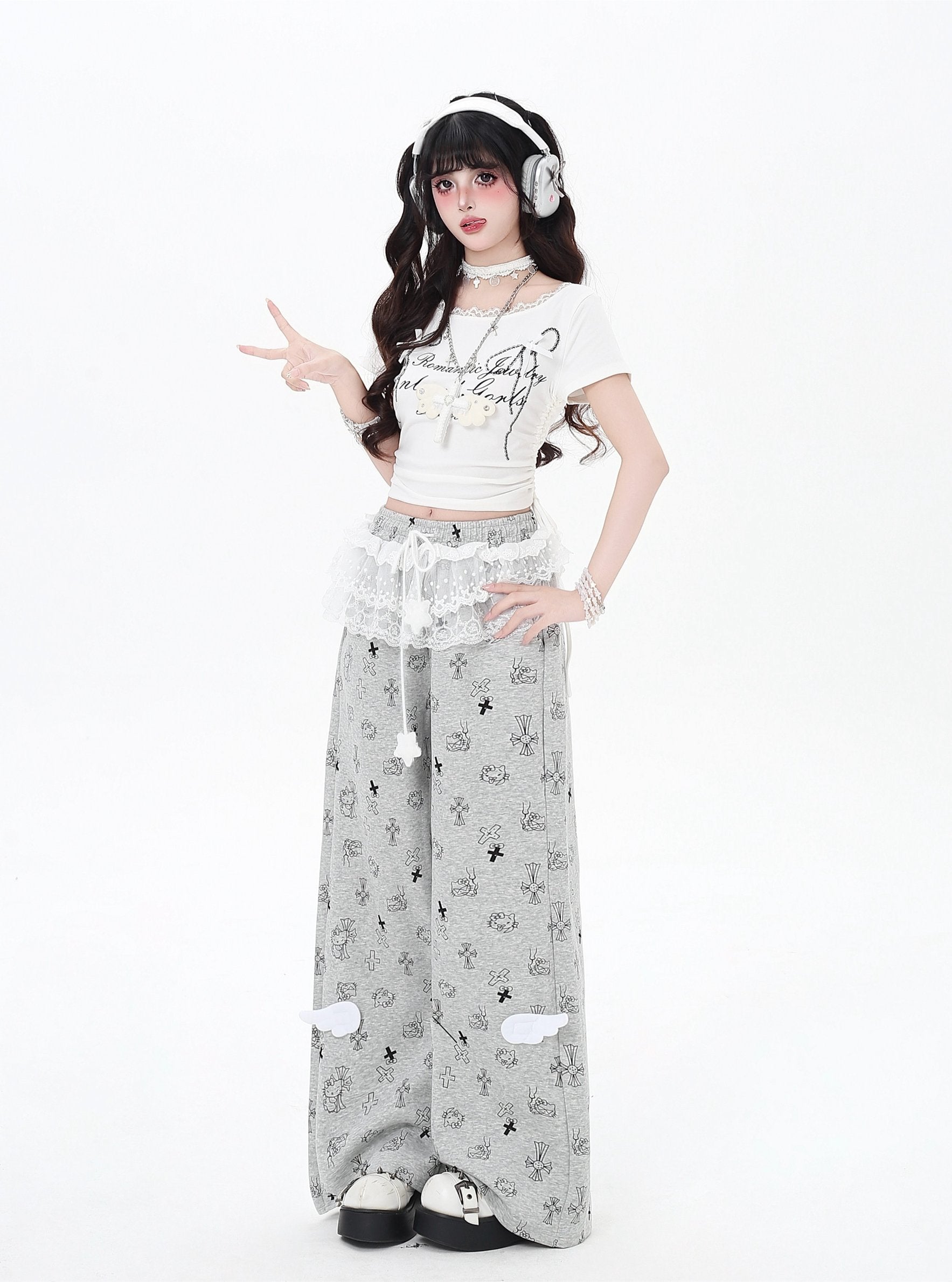 Person wearing a white crop top and gray pants with a pattern, posing on a white background