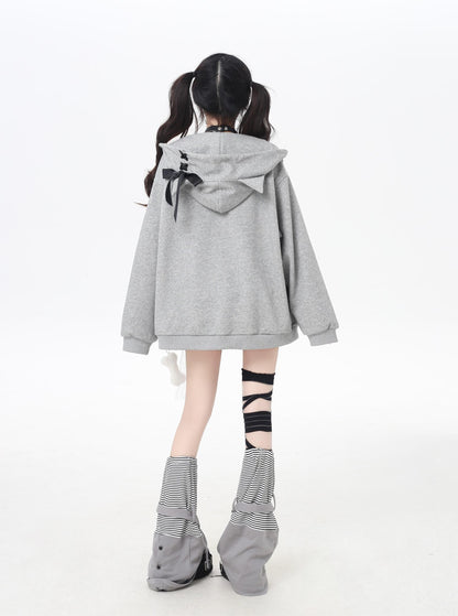 Person wearing a gray hoodie with a bow detail on a white background