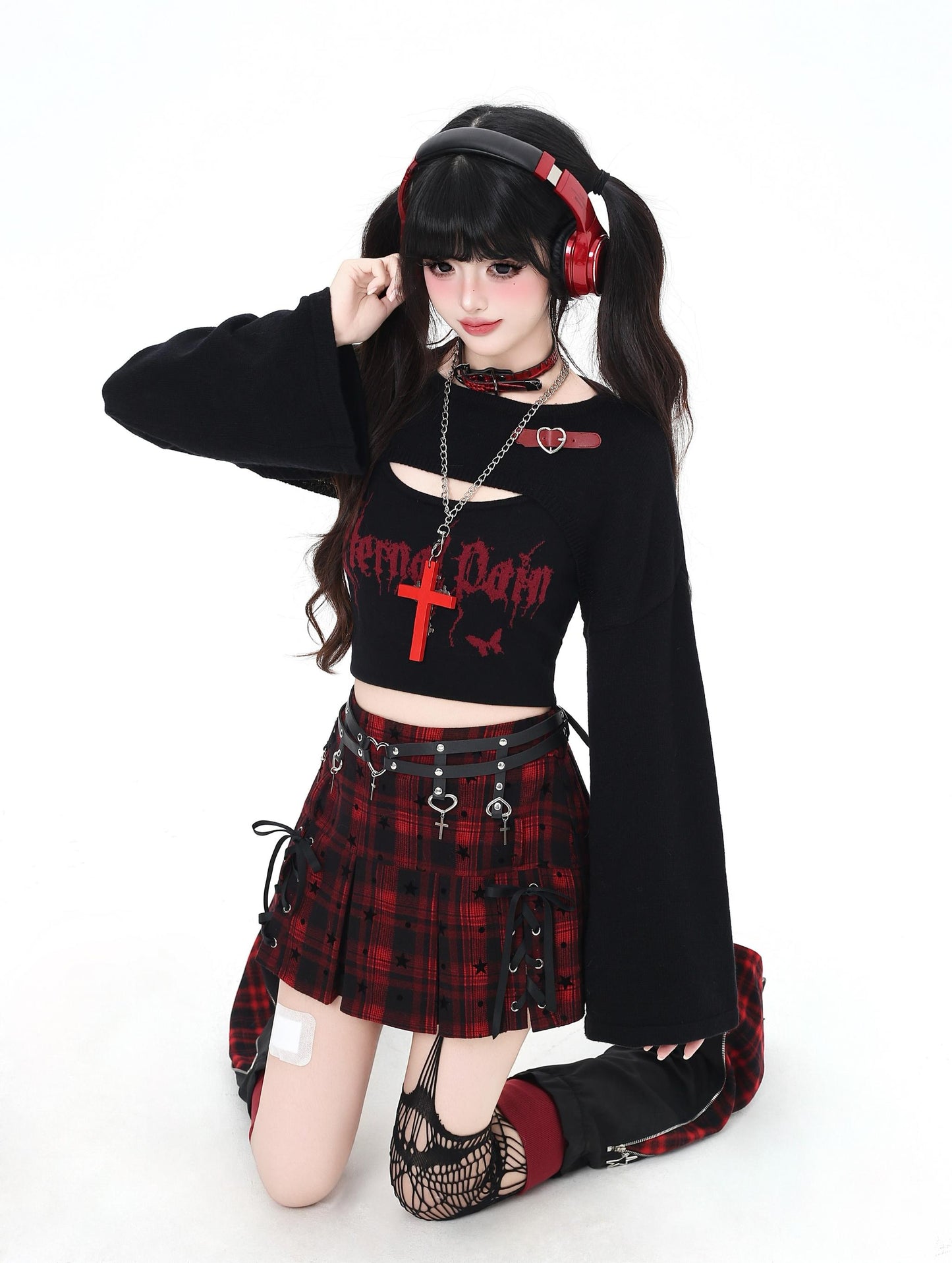 Person wearing a black and red outfit with a plaid skirt and headphones on a white background