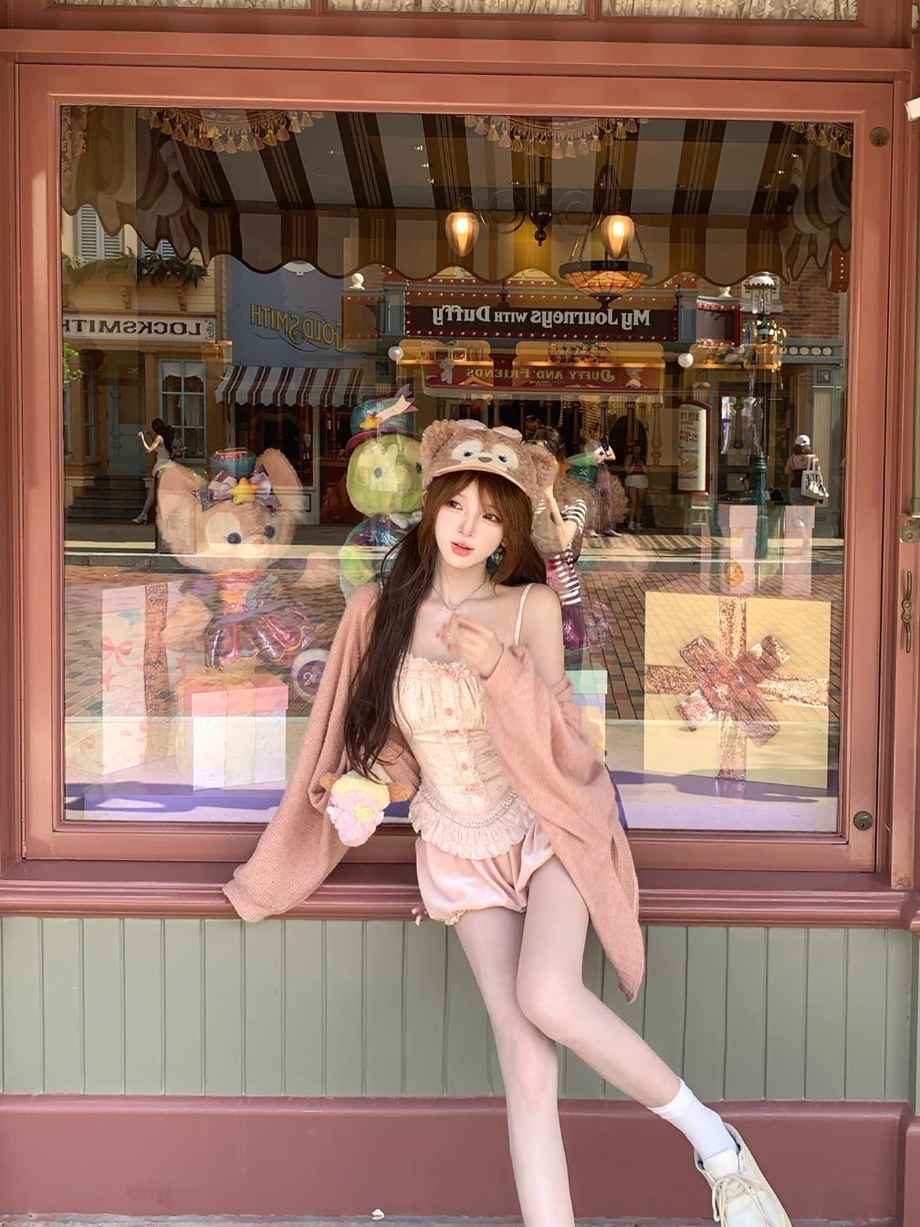 Woman in a coquette pink vintage-style dress standing in front of a store window display.