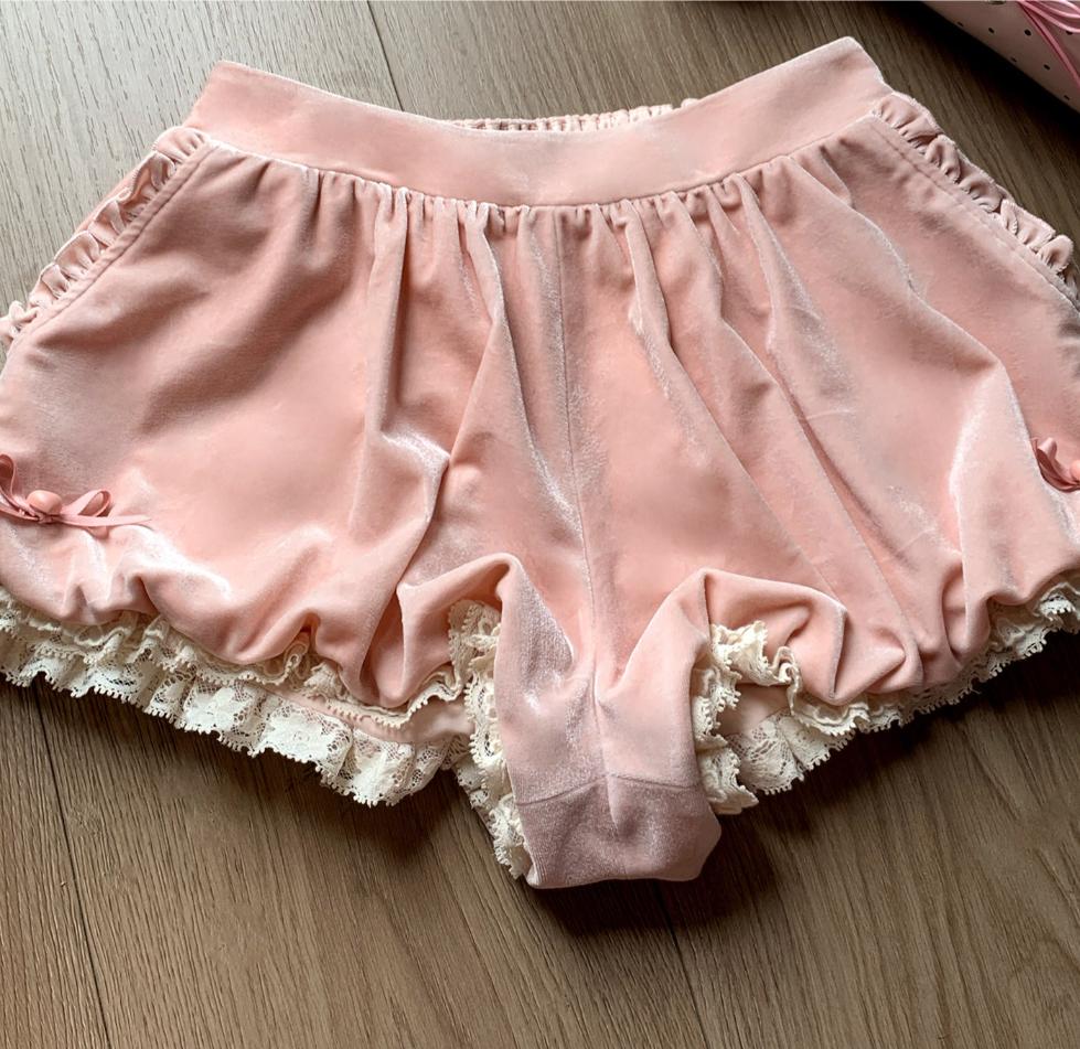 Pink coquette shorts with lace trim on a wooden surface