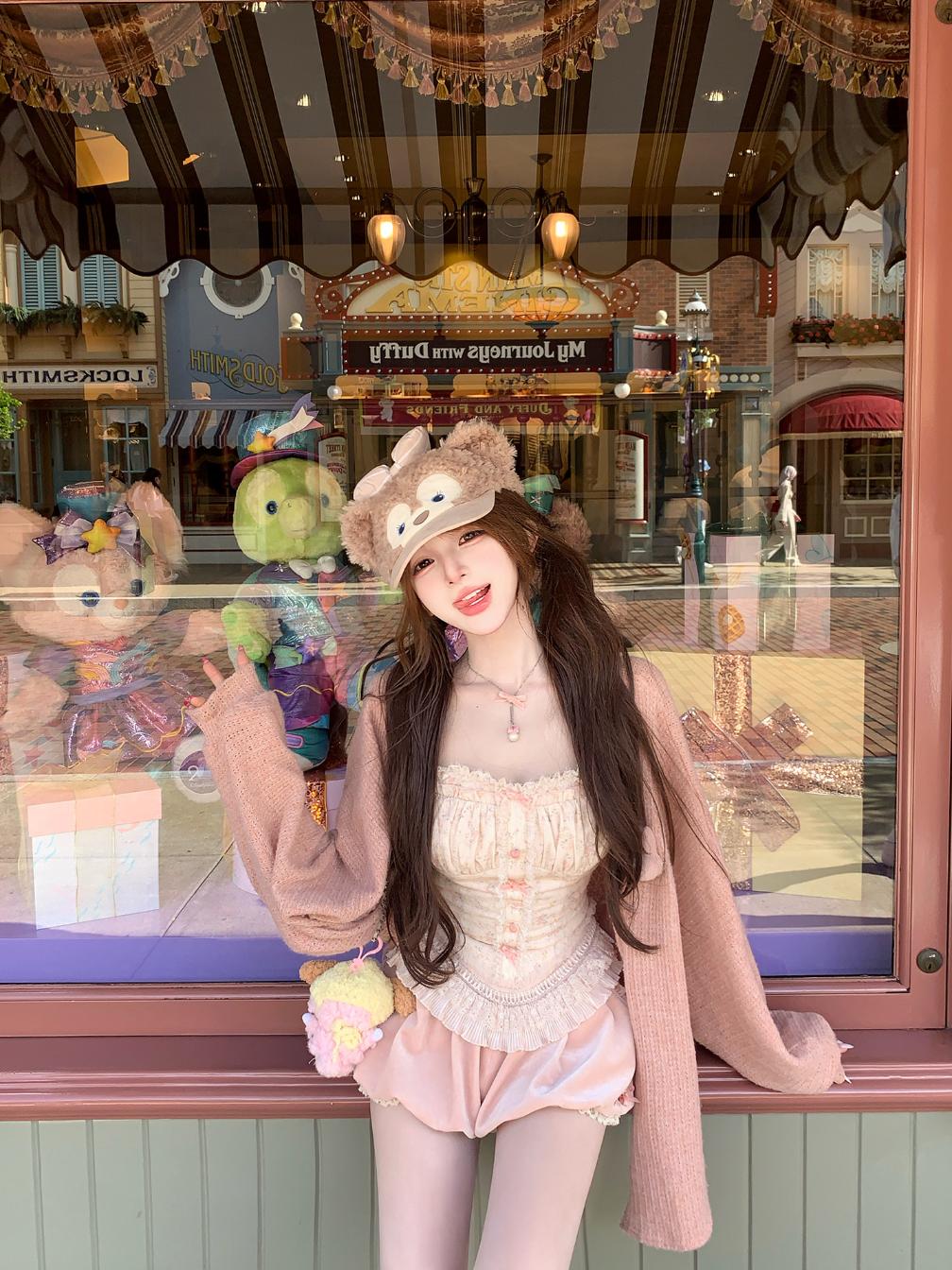 Person wearing a coquette pink outfit with a fluffy hat in front of a store window display.