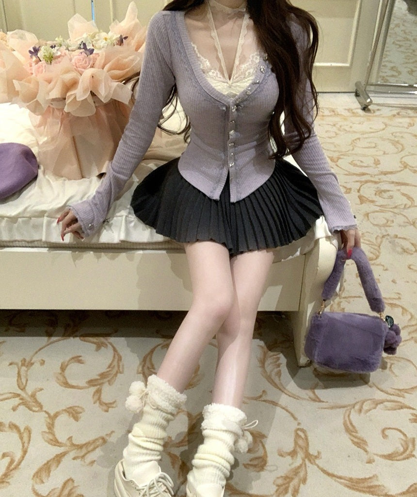 Woman in a stylish outfit with a purple cardigan and black pleated skirt, standing in an elegant room.