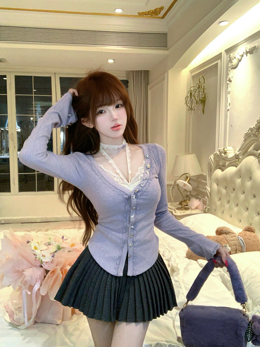 Woman in a light purple cardigan and black pleated skirt standing in a decorated room.