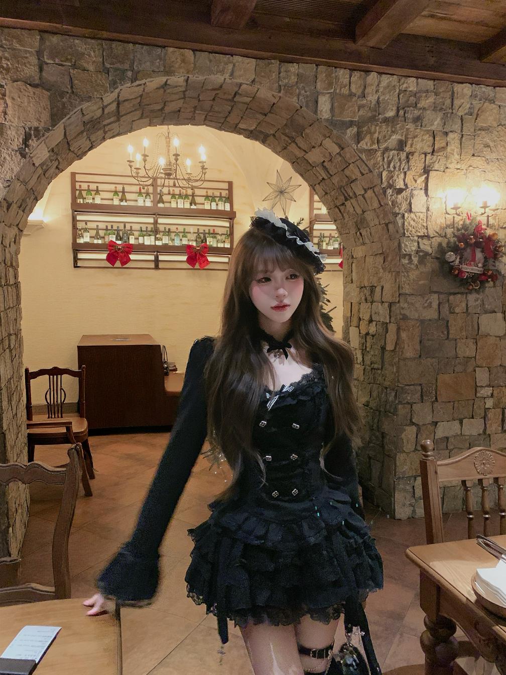 Person in a black outfit with a white lace collar in a stone-walled room.