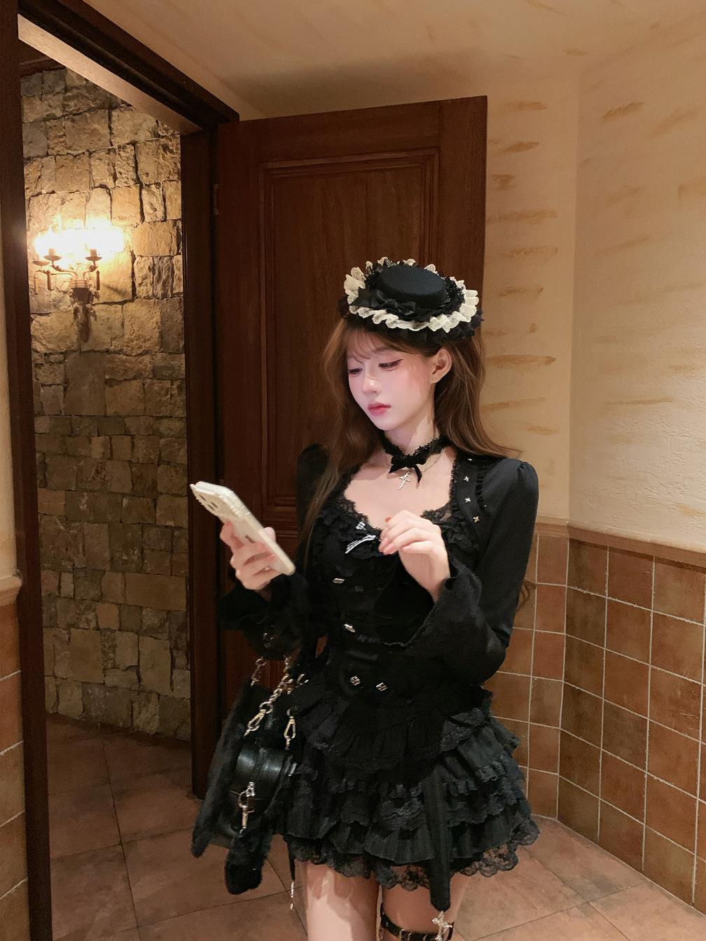 Woman in a black outfit with floral headpiece standing in a room with stone walls and wooden door.