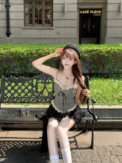 Woman in black dark coquette outfit sitting on a bench in front of a building with 'Café Fleur' sign.