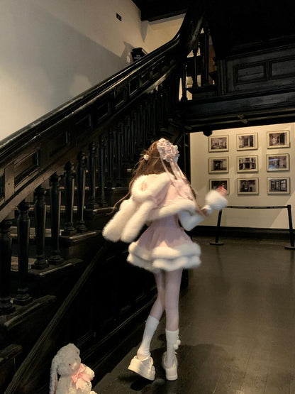 Person in a white outfit with rabbit ears standing on a staircase in an indoor setting.