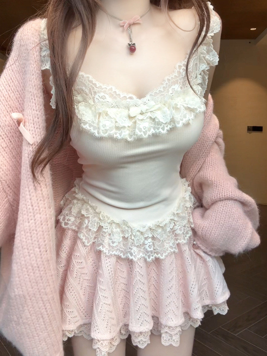 Person wearing a coquette white lace top and skirt with a pink cardigan indoors.