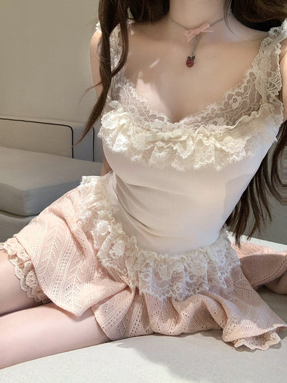 Person wearing a coquette  white lace top and pink lace shorts sitting on a light-colored surface.