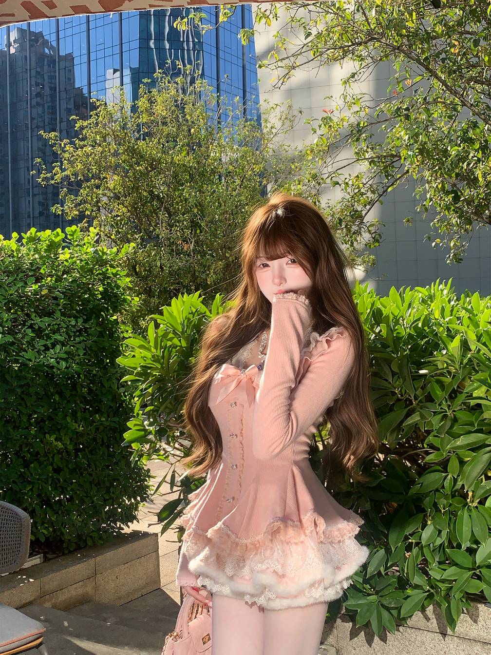 Woman in a pink dress standing outdoors with greenery and buildings in the background