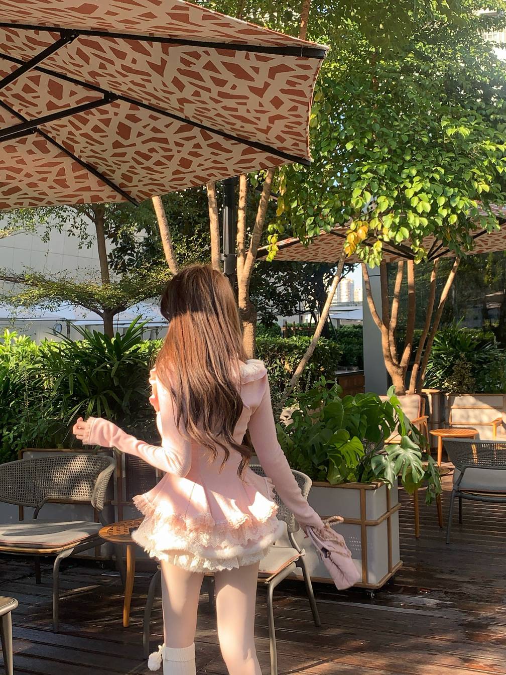 Woman in a pink outfit walking under a leopard print umbrella in an outdoor setting with greenery.