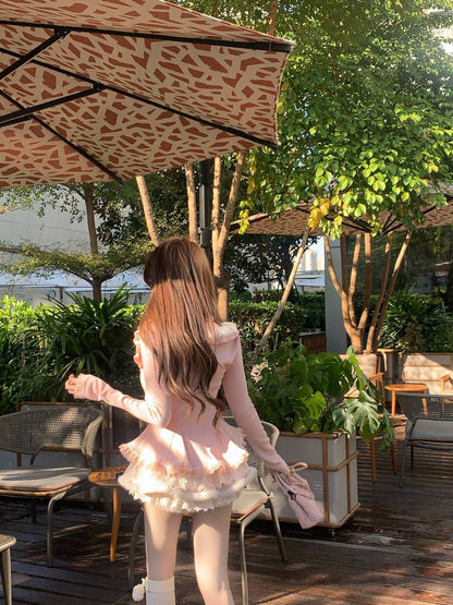 Woman in a pink outfit walking under a leopard print umbrella in an outdoor setting with greenery.