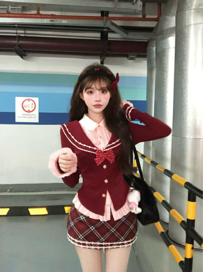 Person in a school uniform with red jacket and plaid skirt standing in an indoor setting.