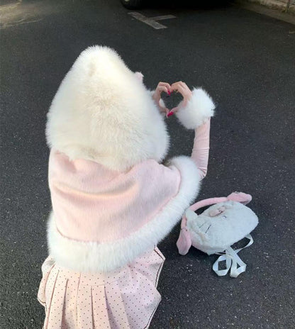 Person wearing a fluffy white hooded coat with a pink backpack on a dark surface.