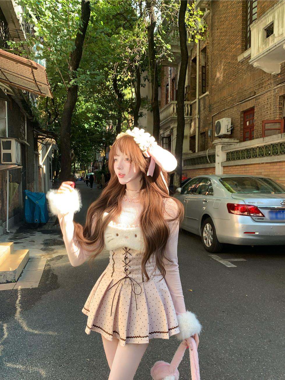 Woman in a pink outfit with bunny ears standing on a street.