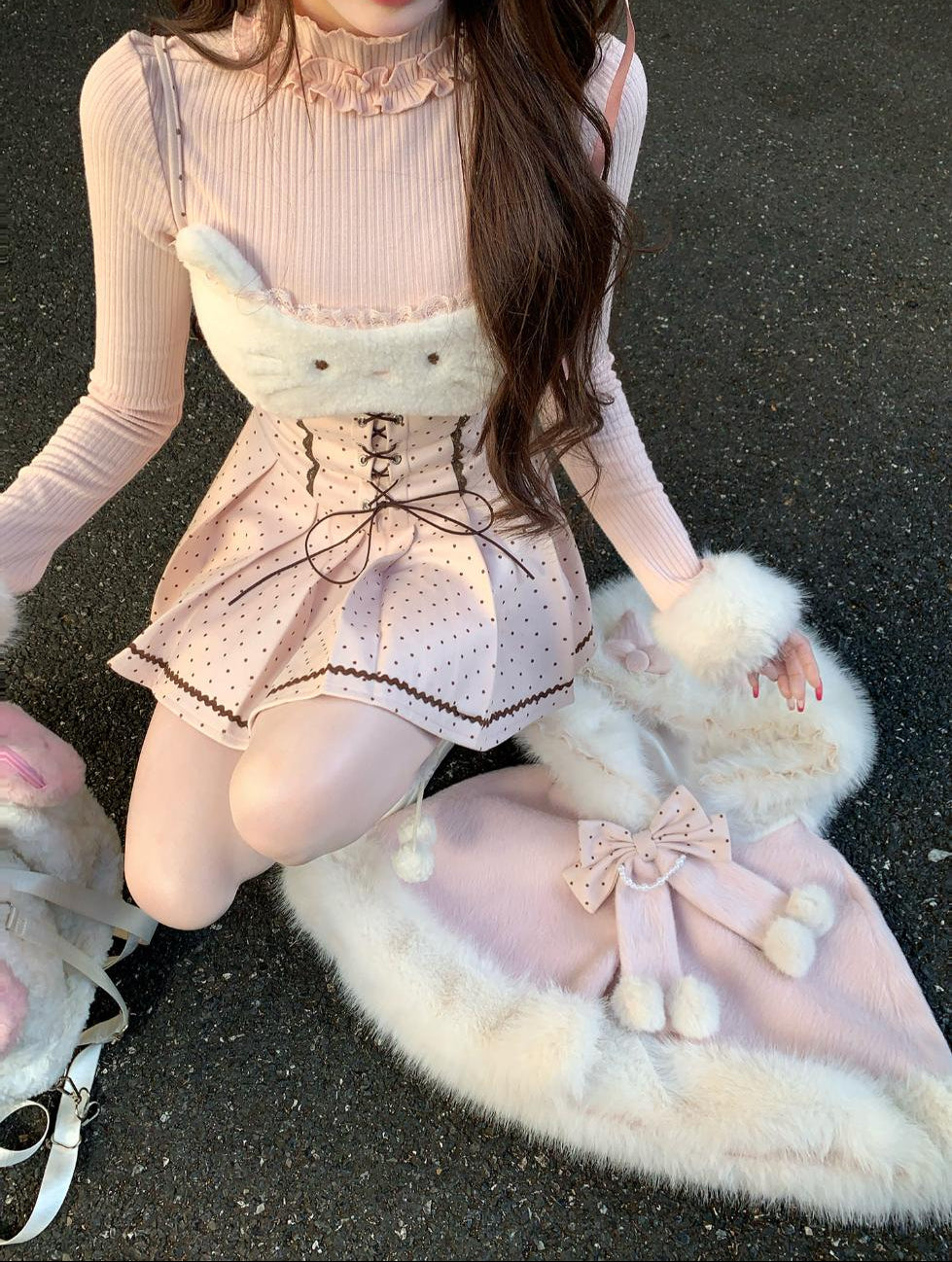 Person wearing a pink cute outfit with a fluffy white skirt on a dark surface