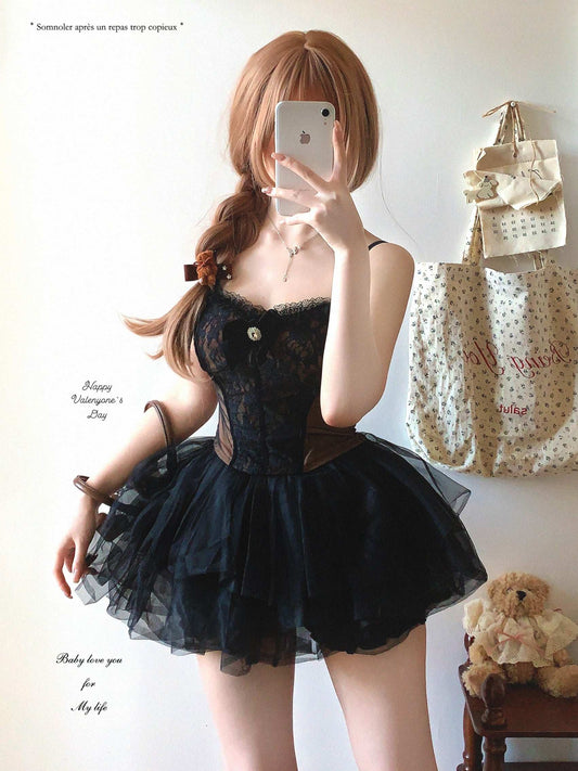 Person wearing a black lace dress taking a mirror selfie in a room with bags and a teddy bear.